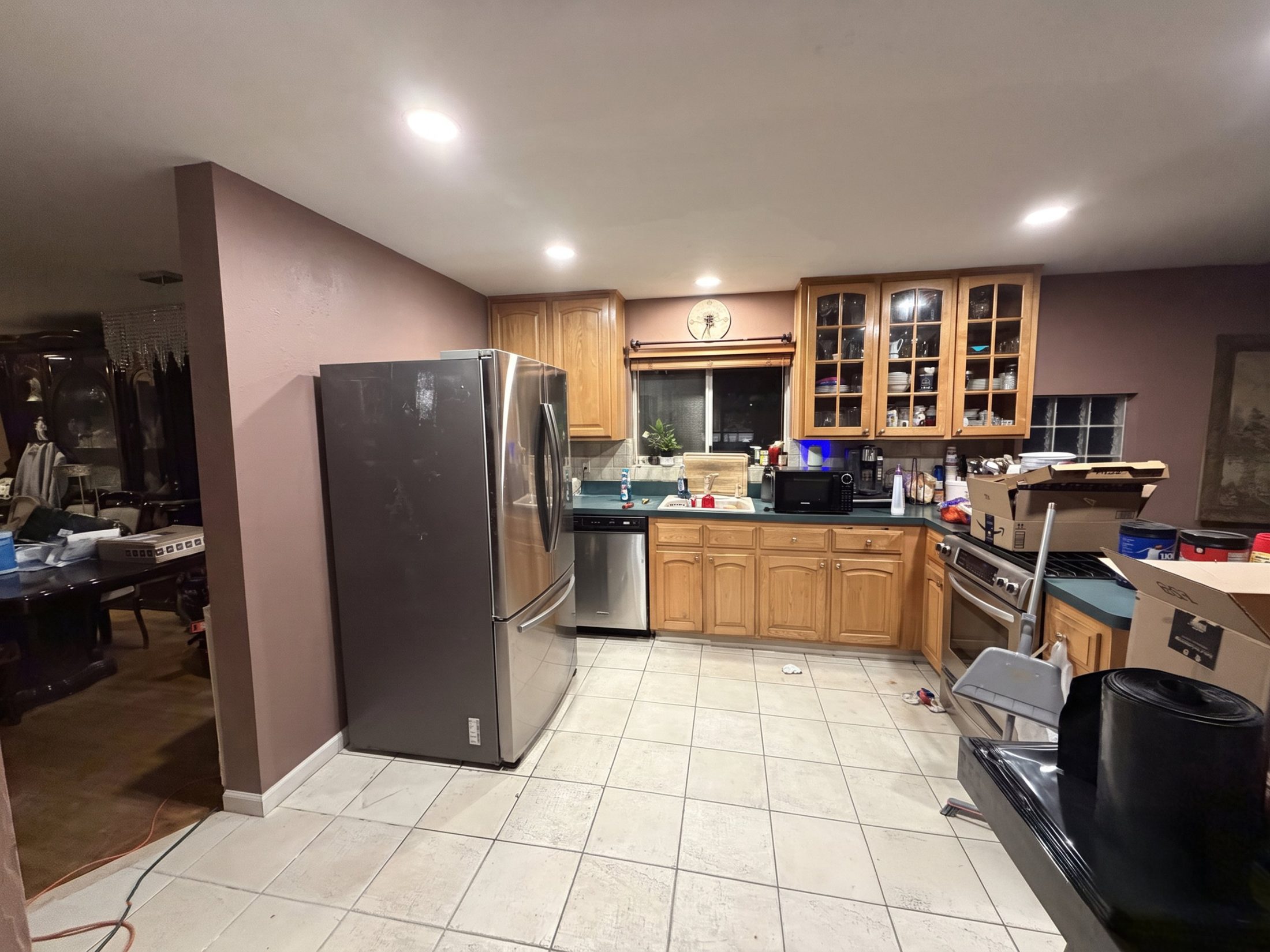 Before: wide view of the original kitchen with oak cabinets, green counters, tile floor and a freestanding refrigerator