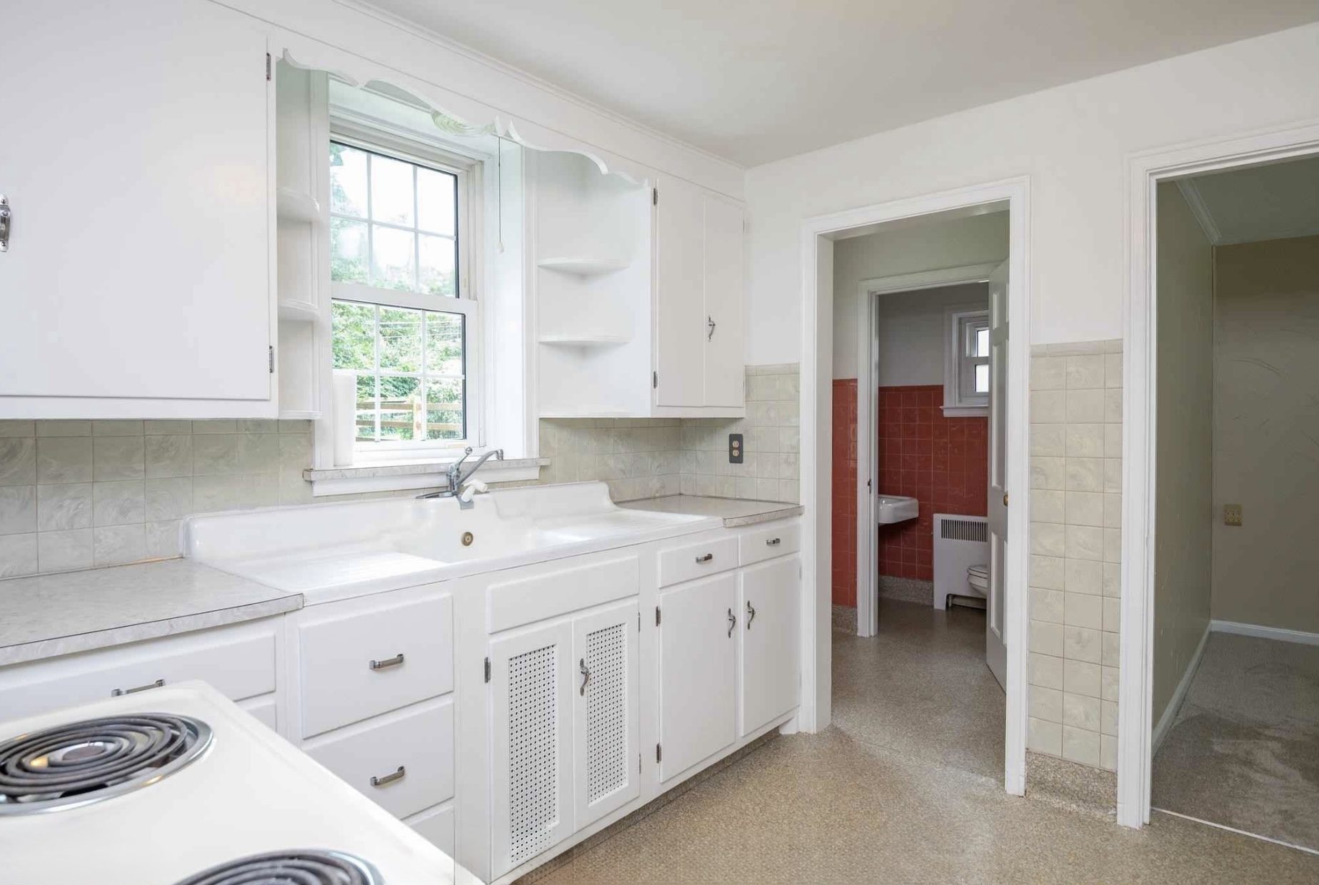 Before: sink wall with the powder room visible through the doorway