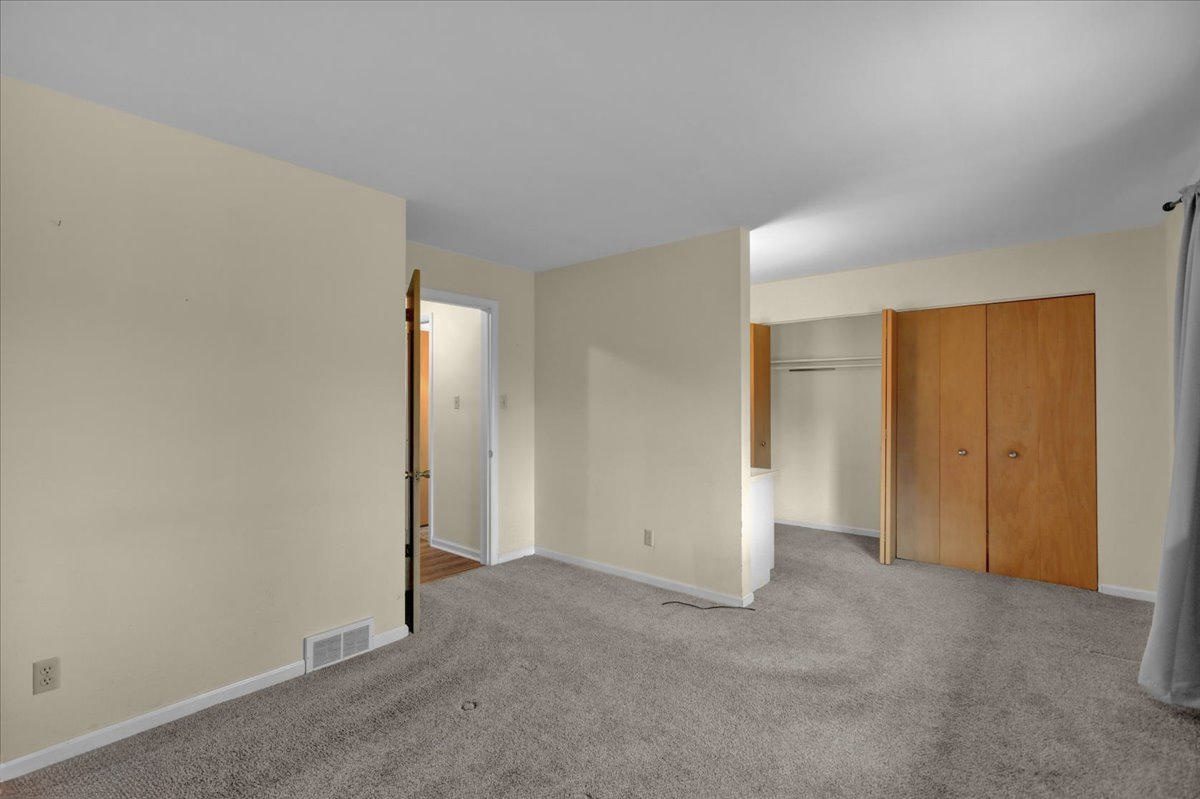 Before: the original bedroom with beige walls, gray carpet and wood bifold closet doors
