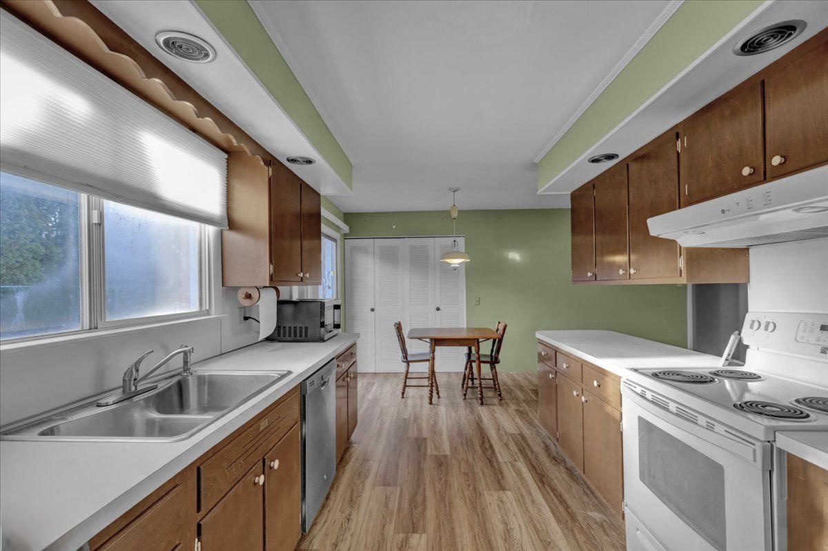 Before: the original galley kitchen with brown cabinets, white laminate counters, green walls and a small dining table
