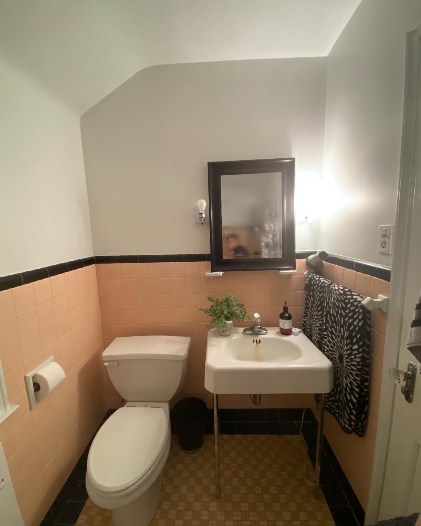 Before: bathroom with peach wall tile, black trim and a pedestal sink