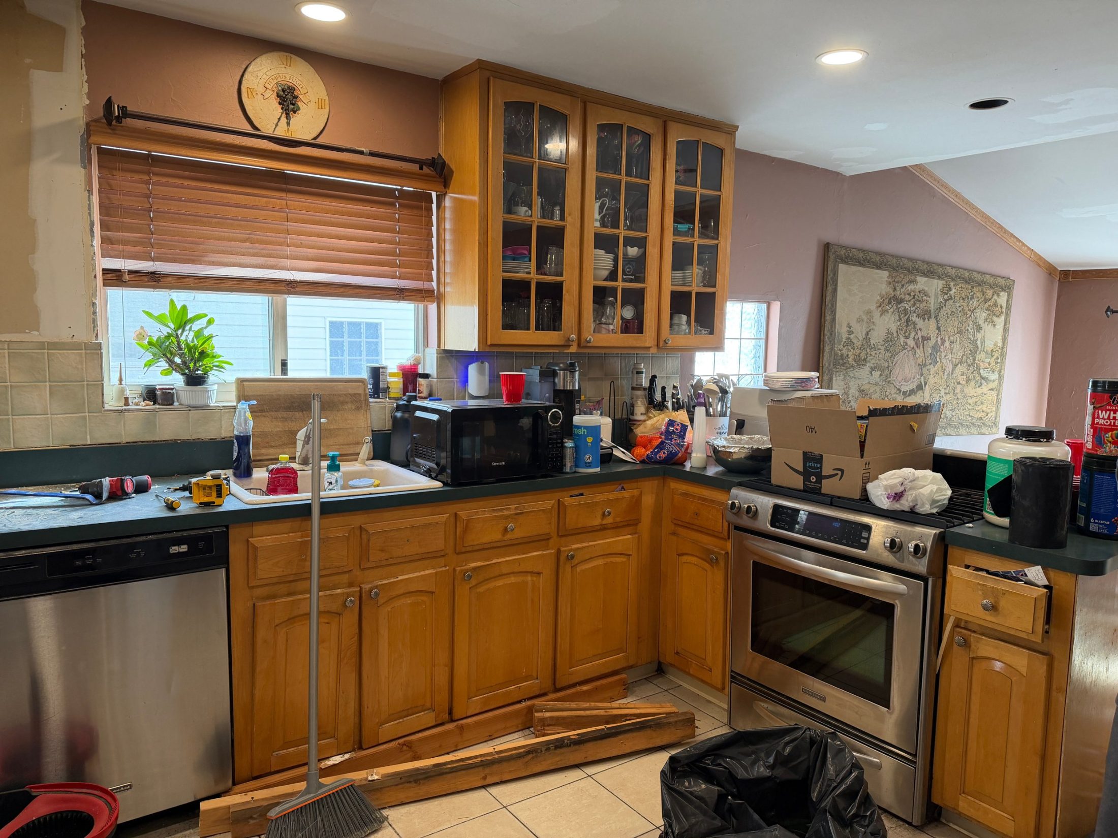 Before: the original kitchen with golden oak cabinets, glass-front uppers, dark green laminate counters and a window over the sink