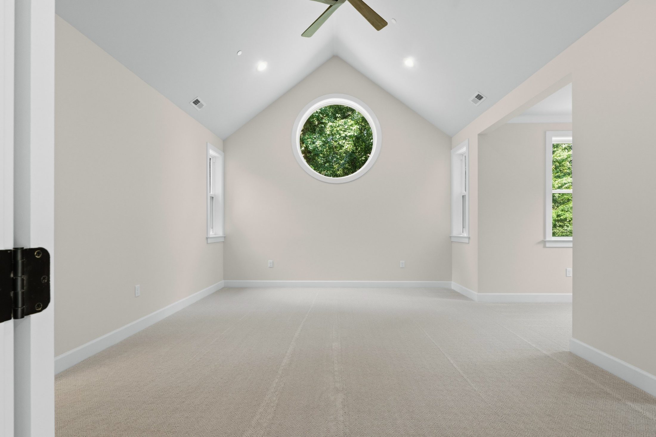 Bedroom with a vaulted ceiling, round window and ceiling fan